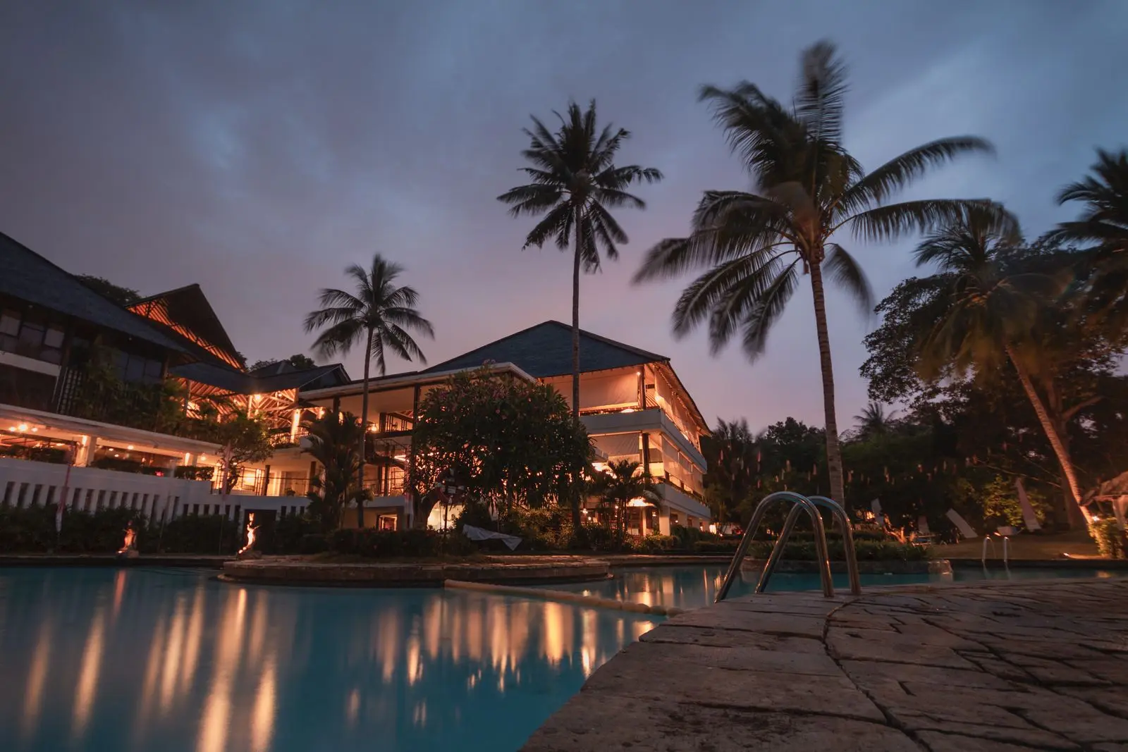 Palm trees and a lit resort at dusk
