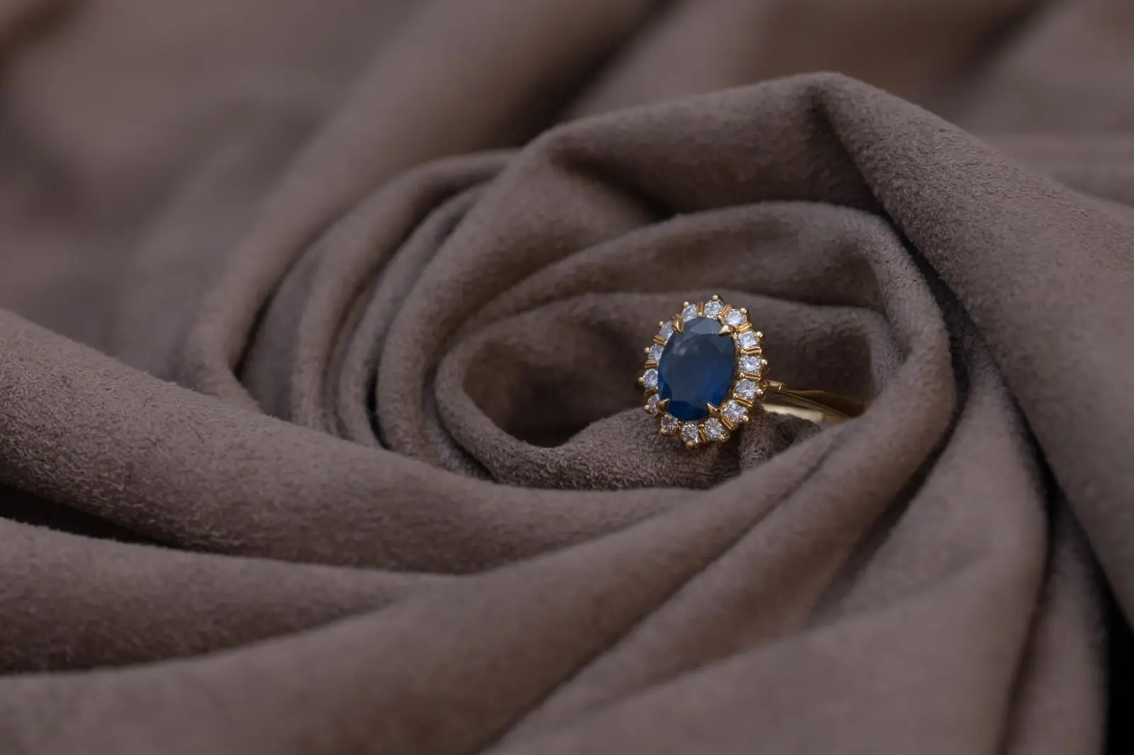 A gold ring with a sapphire resting on silk